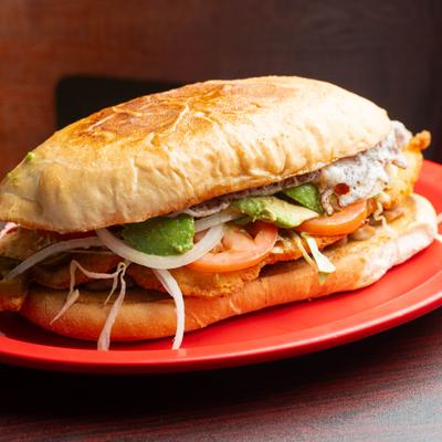 Torta Milanesa sandwich with breaded chicken, avocado, and tomato.