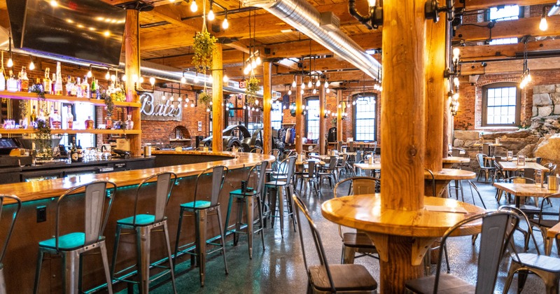 Seating area, tables and chairs, and a bar with bar stools on the left