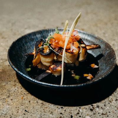 Grilled skewered seafood topped with diced tomatoes.