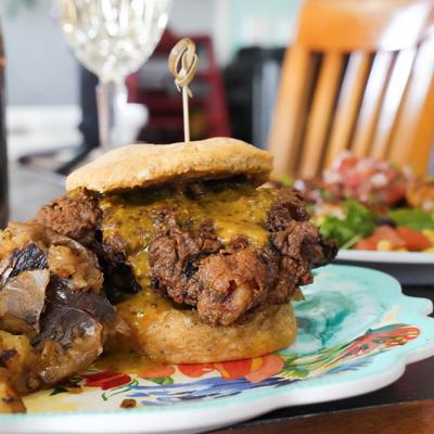 Crispy fried chicken sandwich with melted cheese and smashed potatoes on the side.