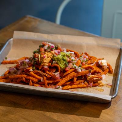 Vegan sweet potato fries dressed with chipotle hummus, guacamole, and salsa fresca.