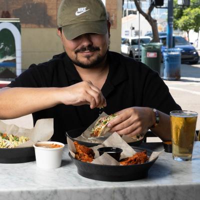man eating tacos with beer.