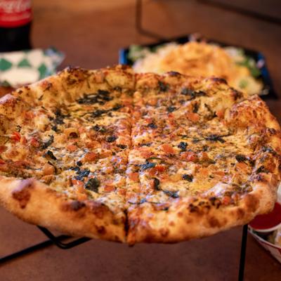 Whole Margherita Pizza served on pizza stand.