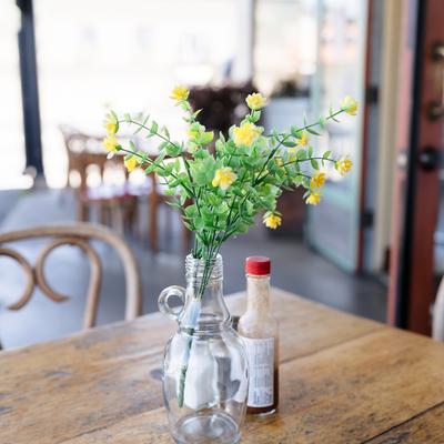 Table with a vase with artificial flowers and condiments, close-up.
