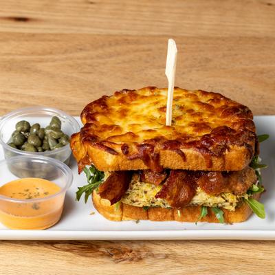 Bacon Egg And Cheese Omelette Sandwich accompanied by capers and a dipping sauce.