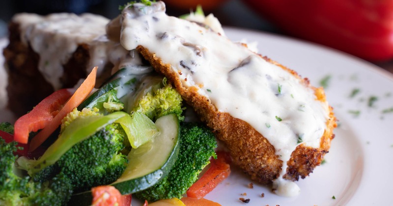 Crumbed chicken breast served with vegetables