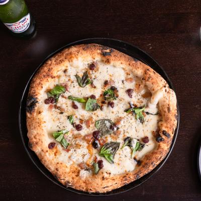 Pizza with mozzarella, cured meat, pecorino cheese, thyme, and caramelized onion.