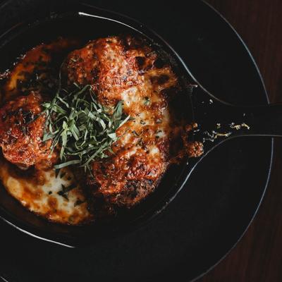 Homemade meatballs topped with vodka sauce, Parmesan, and herbs.