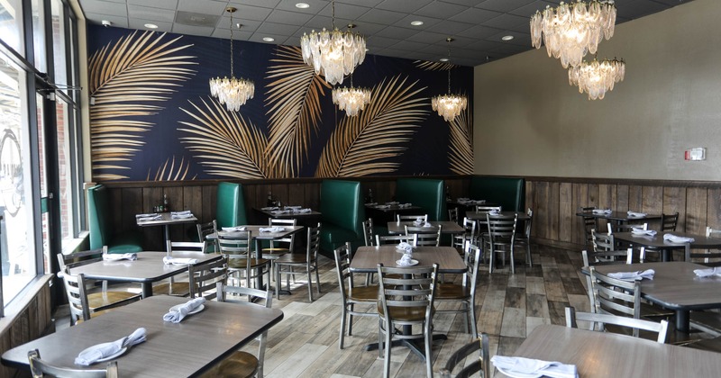 Interior, dining area, seating booths, tables for four and two, large palm leaves mural on the wall