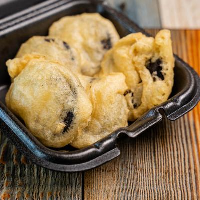 Deep-fried Oreos served in a black, takeout container.