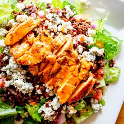 Grilled chicken salad with lettuce, bacon bits, and blue cheese.