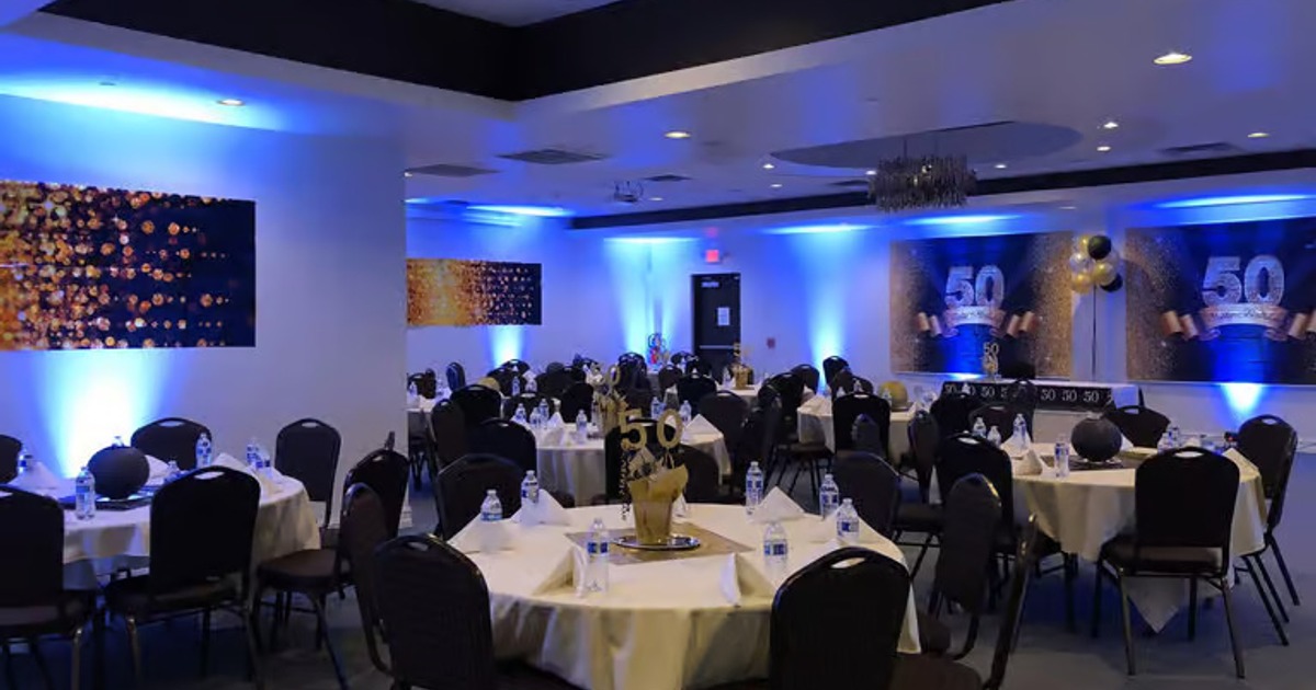 Modern decor with blue uplighting and several round tables set for guests