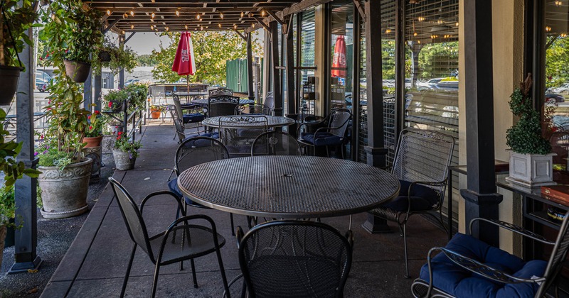 Outdoor terrace with metal tables, chairs, and overhead string lights