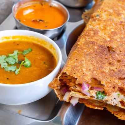 Onion dosa served with lentil stew and two chutneys.