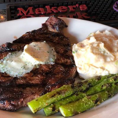 Grilled steak with butter, asparagus, and mashed potatoes.