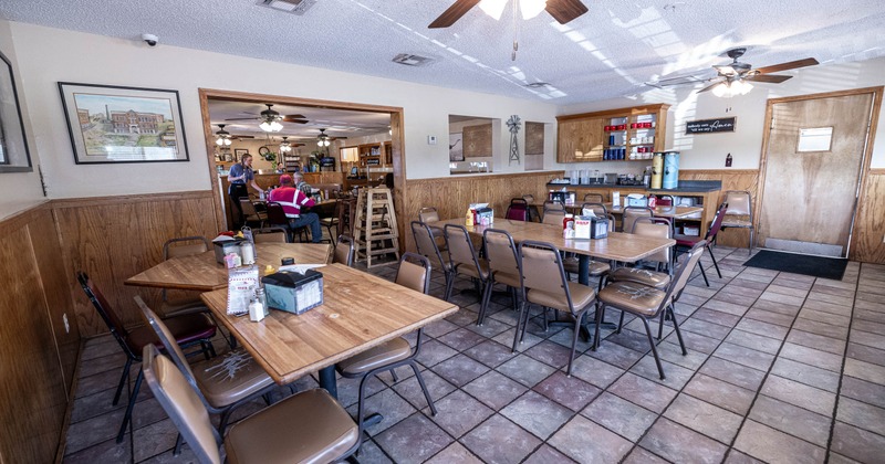 Casual dining area with empty wooden tables and chairs on tiled floor