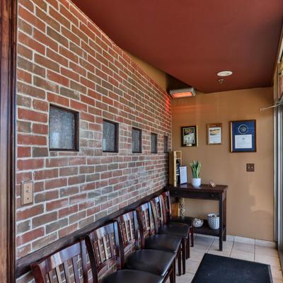 Waiting area with long brick wall and a row of wooden chairs.