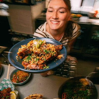 Person holding a plate of glazed fried pieces in a kitchen setting.
