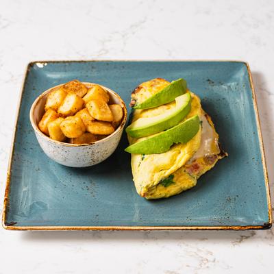 An avocado omelet served with a side of breakfast potatoes on a teal plate.