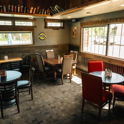 Sunlit dining area with wooden tables and mismatched chairs.