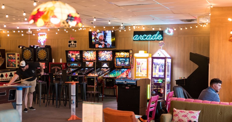 Interior with pinball machines, arcade cabinets, a pool table,and a claw machine