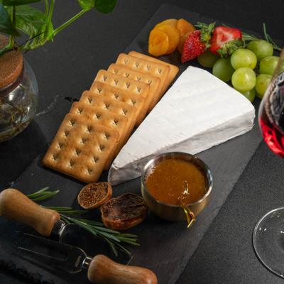 Brie cheese board, with crackers, fresh fruit, fruit preserve, and dried figs.