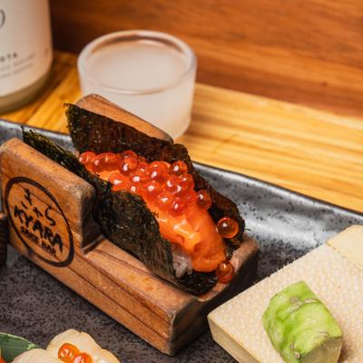 Hand-rolled sushi served on a small, custom wooden holder.