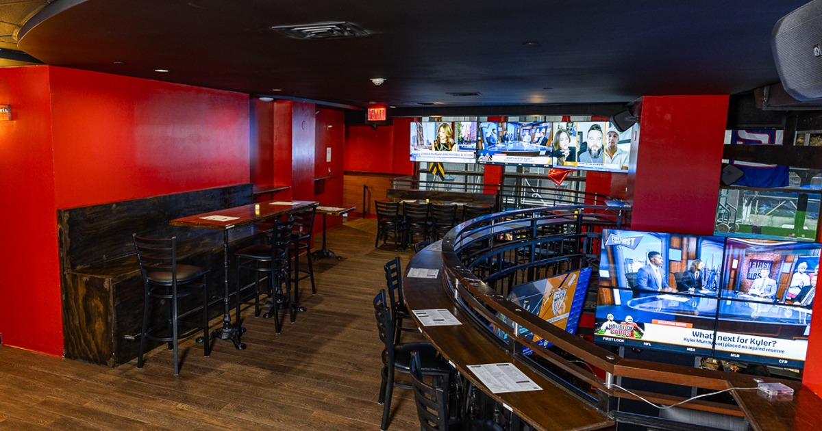 Upper level bar seating with a seatnig space and TV screens