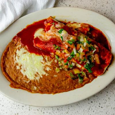 Burrito smothered in red sauce, with salsa, and refried beans.