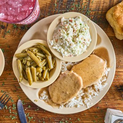 Sliced pork loin with gravy, mushrooms, green beans, and coleslaw.