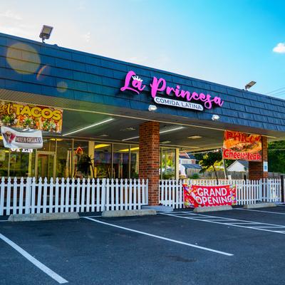 Exterior, angle view to restaurant, entrance, sign above, part of parking lot in front.