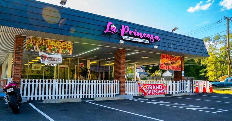 Exterior, angle view to restaurant, entrance, sign above, part of parking lot in front