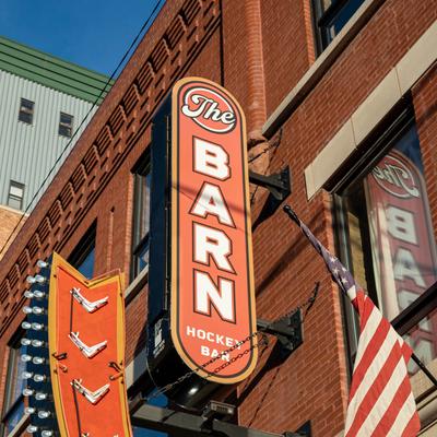 Exterior, the Barn Hockey Bar blade sign on a red brick building.