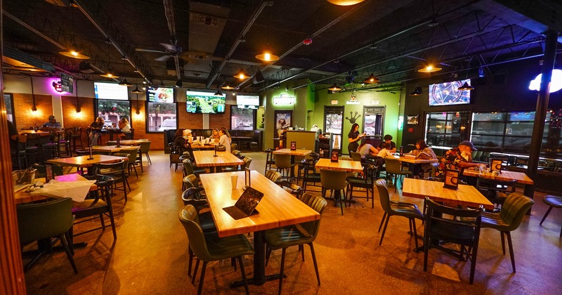 A cozy bar interior with wooden tables, green chairs