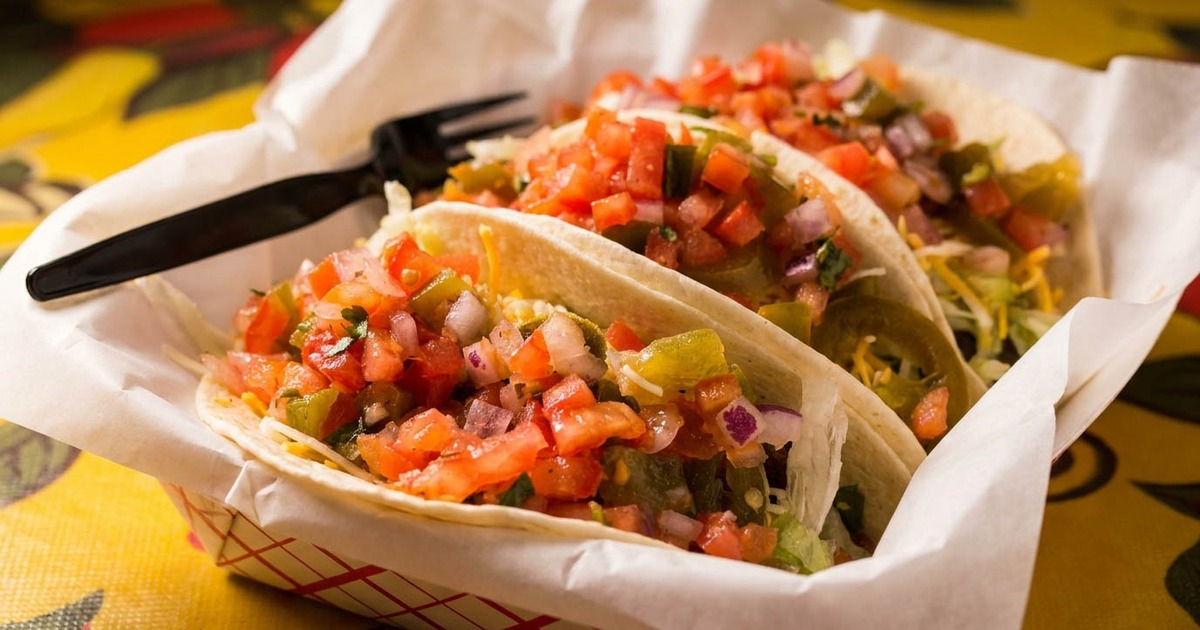 Three fresh street tacos piled high with vibrant tomato salsa