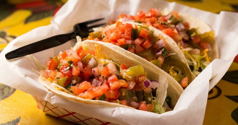 Three fresh street tacos piled high with vibrant tomato salsa