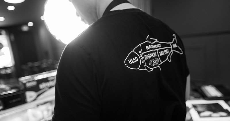 Employee wearing a t-shirt with a graphic design that illustrates the different cuts of a fish