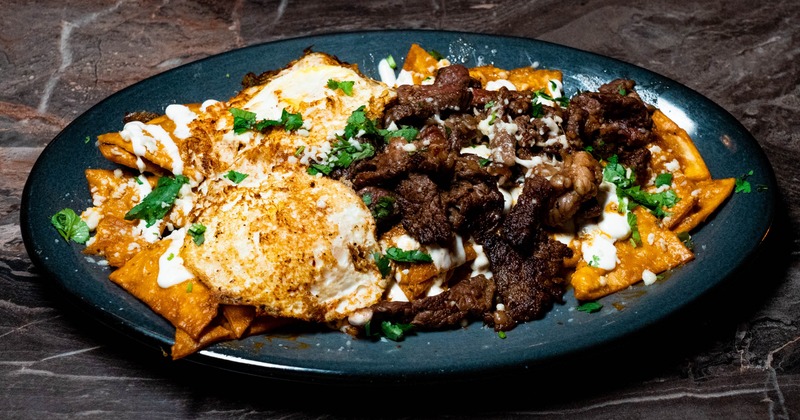 Chilaquiles del Rancho with fried eggs, steak and a sauce drizzle