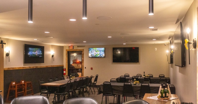 Interior with tables, chairs and multiple large-screen televisions on the walls