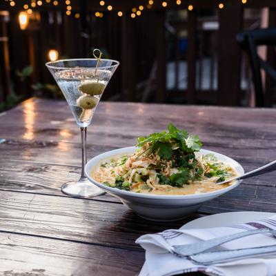 Laksa Malasian Noodles served on the table alongside a Martini cocktail.