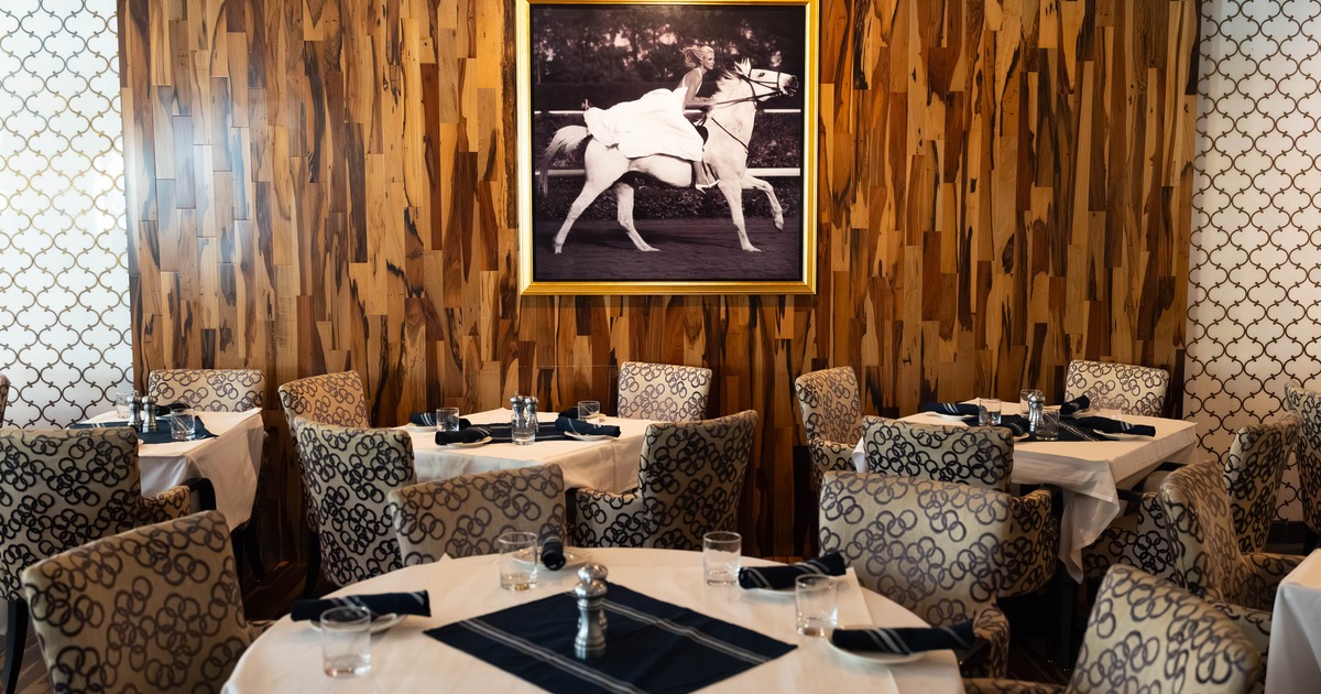 Interior - round tables, patterned chairs, wood-paneled walls and a large framed photograph.