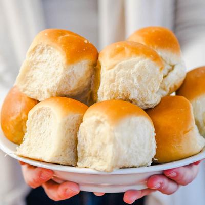 A person holds a plate with rolls on it.