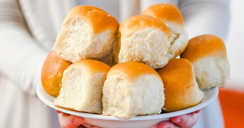 A person holds a plate with rolls on it