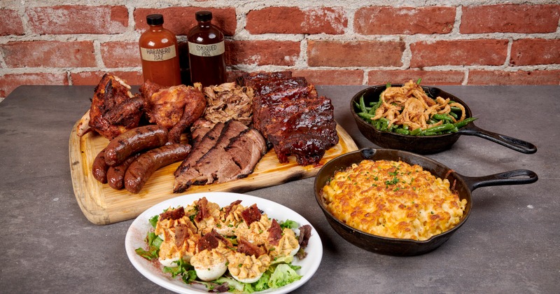 A BBQ meat platter, a skillet with green beans and fried onions, mac and cheese and deviled eggs