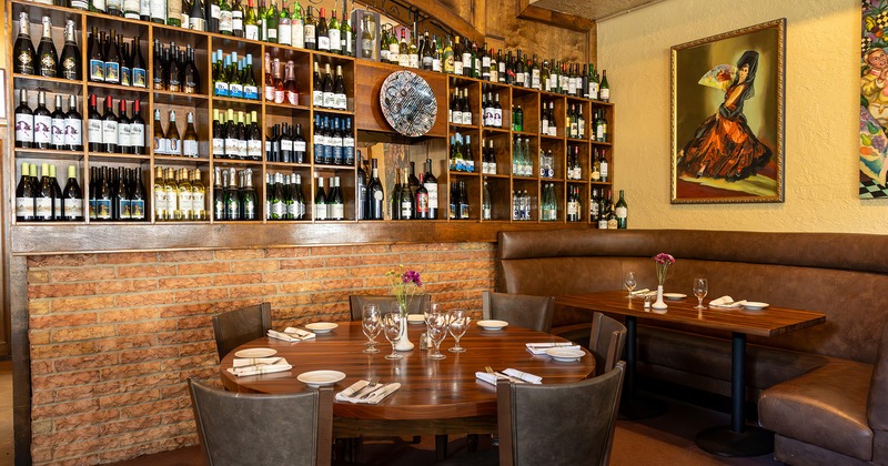 Dining tables set for guests and wine shelves with assorted wines