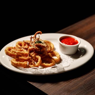 Fried calamari served on a plate with marinara on the side.