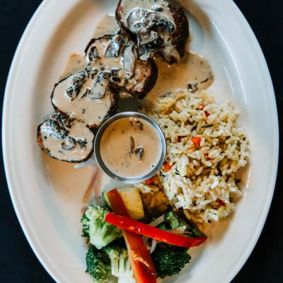 Pork tenderloins covered in a creamy mushroom sauce, served with rice and sauteed veggies.