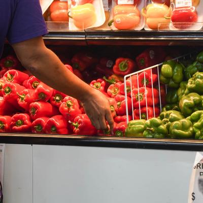 Red and green bell peppers in a grocery store produce section.