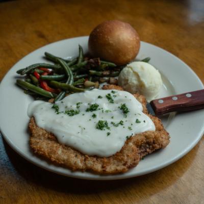 Chicken-fried steak with creamy gravy, green beans, and mashed potatoes.