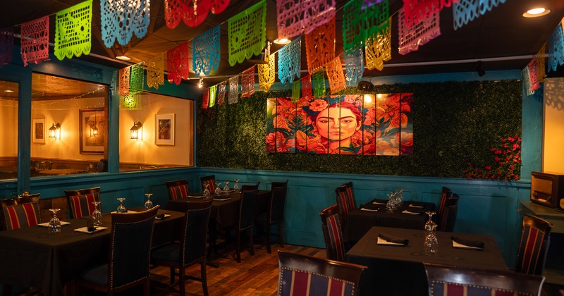 Interior of cozy Mexican-style dining area decorated with hanging paper ornaments